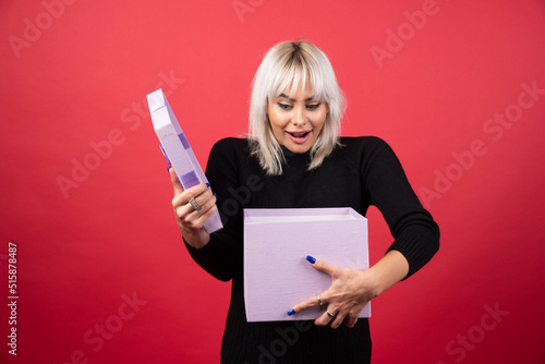 Young woman excited about a present on a red background