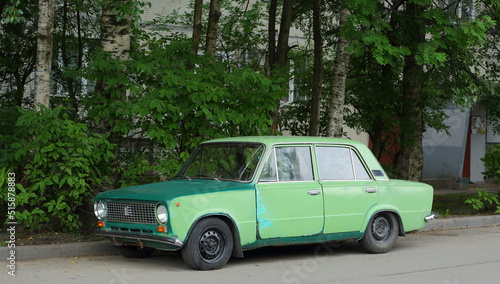 Old green Soviet car in the courtyard of a residential building, Dybenko Street, St. Petersburg, Russia, July 2022 © Станислав Вершинин