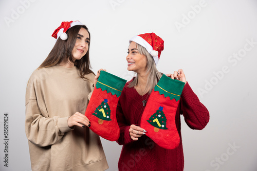 Two smiling girls in Santa hat showing Christmas socks
