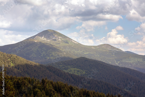 The top of Mount Hoverla is covered with green grass and stones on a sunny day, Hiking and tourism in Carpathians