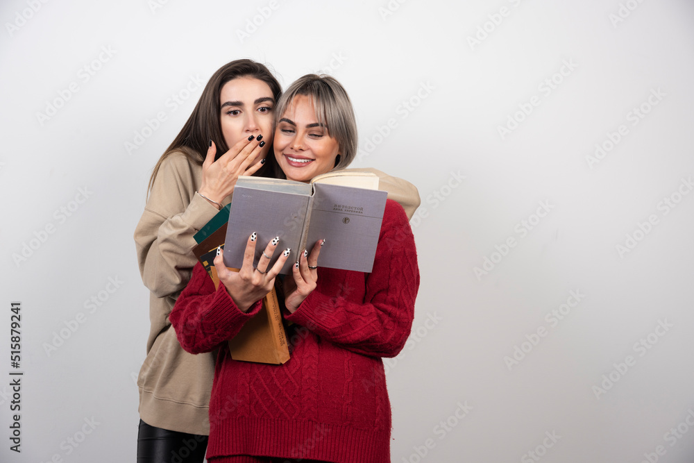 Two friends holding and reading books on a white background Two friends holding and reading books on a white background