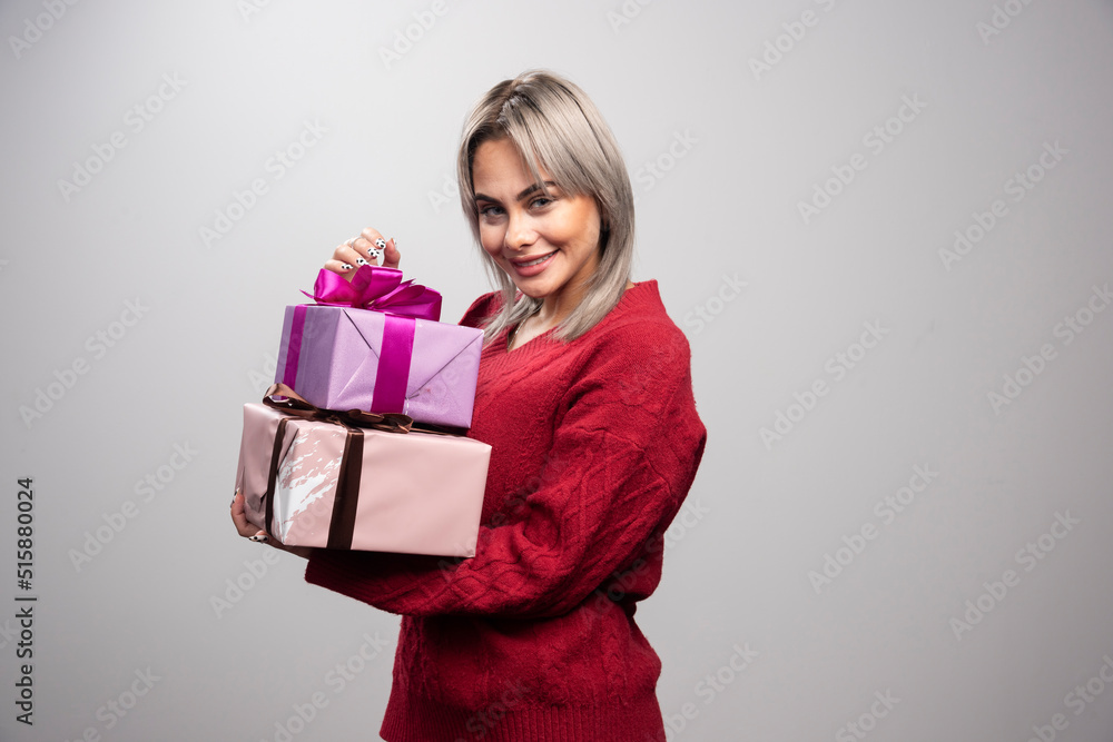 Portrait of woman holding at gift boxes on gray background Portrait of woman holding at gift boxes on gray background