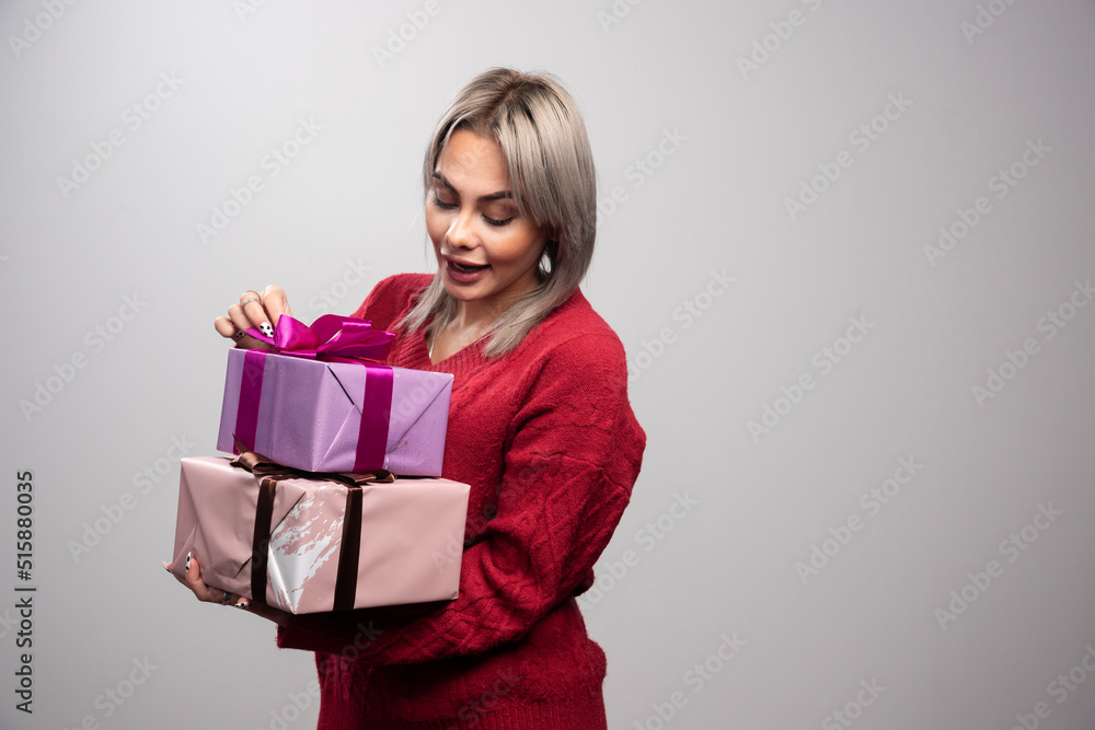 Portrait of woman looking at gift boxes on gray background Portrait of woman looking at gift boxes on gray background