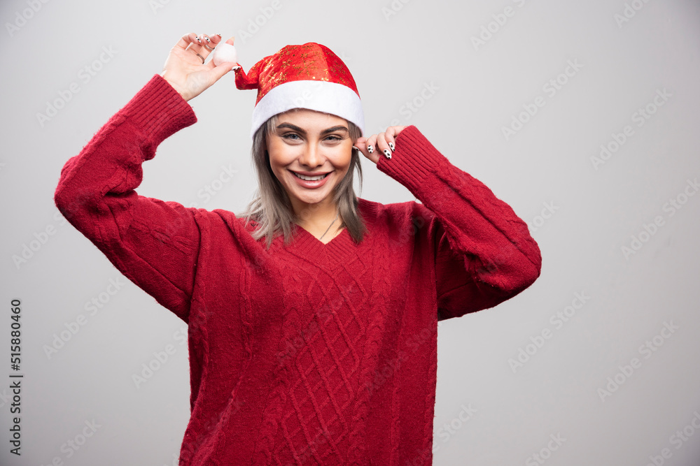 Smiling woman in Santa hat posing on gray background Smiling woman in Santa hat posing on gray background