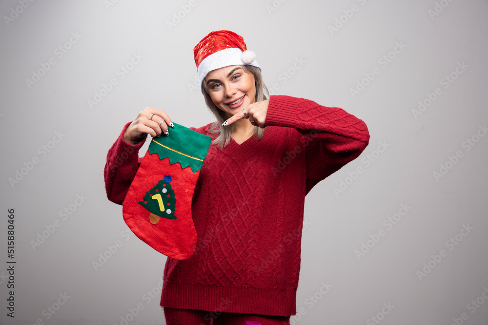 Woman in Santa hat pointing at Christmas stocking