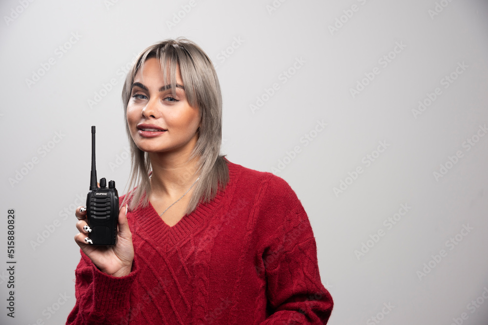 Businesswoman with radio transceiver standing on gray background Businesswoman with radio transceiver standing on gray background