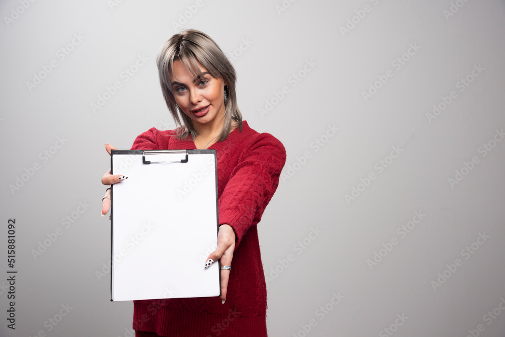 Young businessman showing clipboard on gray background Young businessman showing clipboard on gray background