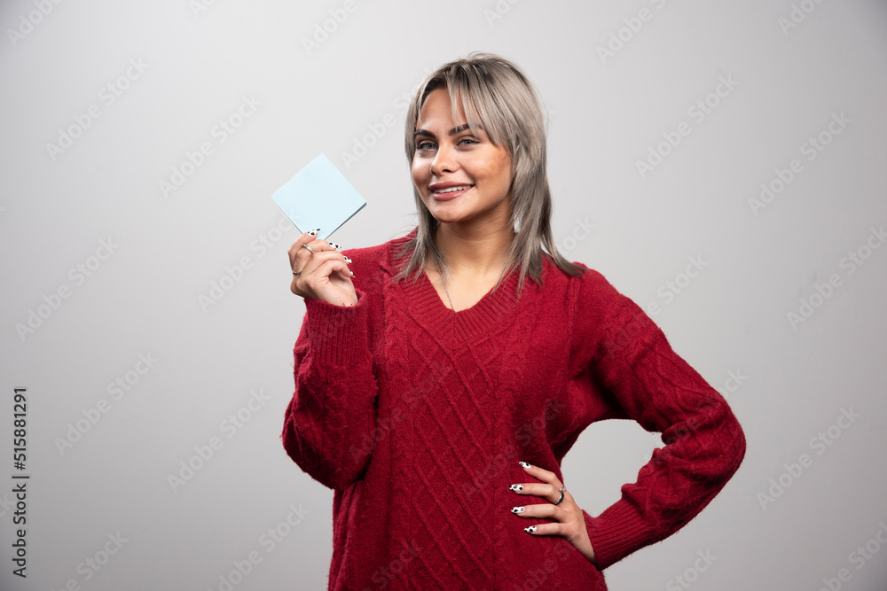 Woman showing memo pad and smiling on gray background Woman showing memo pad and smiling on gray background
