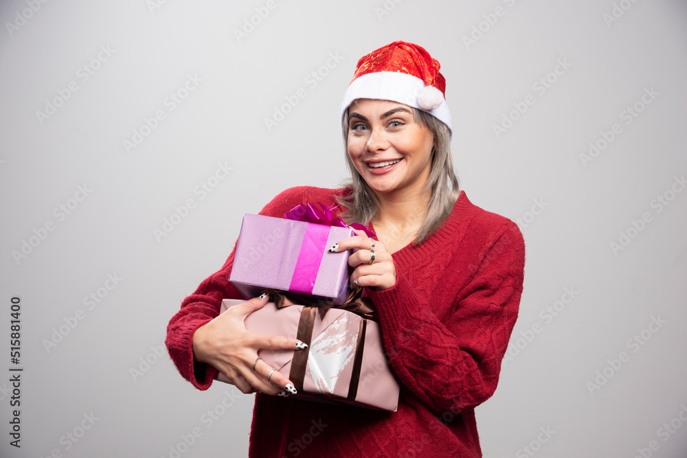 Beautiful woman with Christmas gifts posing on gray background Beautiful woman with Christmas gifts posing on gray background