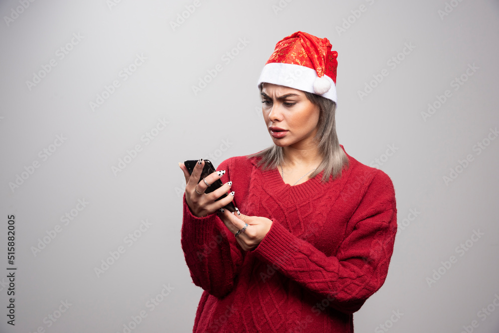 Woman in Santa hat looking at cellphone Woman in Santa hat looking at cellphone