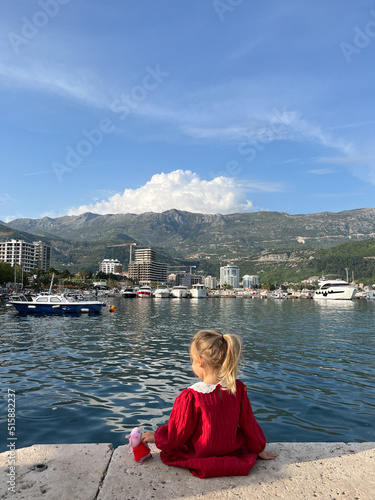 Little girl sits on a pier overlooking the city © Nadtochiy