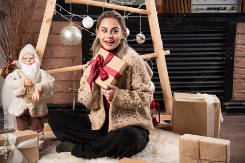 Portrait of pretty woman sitting and holding a Christmas present