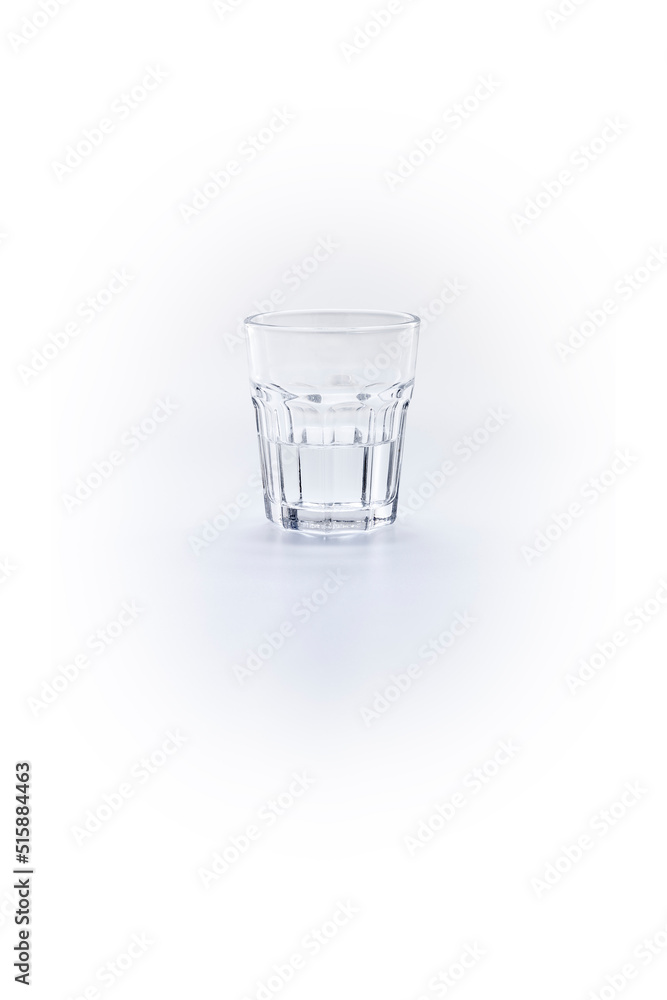 Clear glass half filled with water on a white background Clear glass half filled with water on a white background