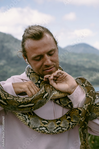 Young man holding a python snake. Bali, Indonesia. Tourism in Bali.