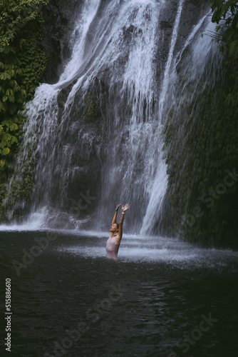A young woman swims in a mountain waterfall in Bali. Travel to Bali.