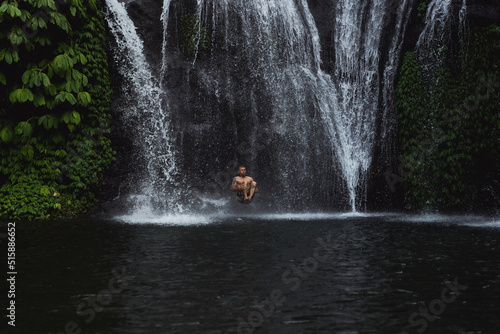 Young athletic man swims in a mountain waterfall, Bali landscape, Indonesia. Tourism in Bali. © Yuliya Kirayonak