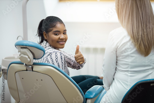 happy young woman with hand gesture in dentist chair