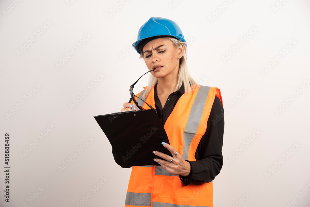 Serious woman builder with helmet looking on clipboard Serious woman builder with helmet looking on clipboard