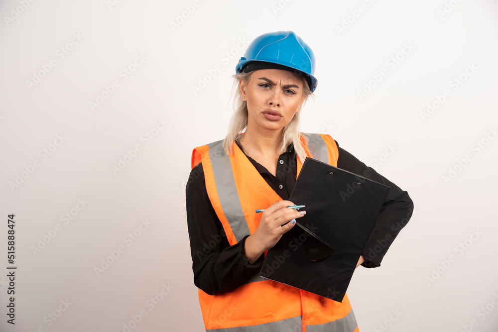 Young woman builder with helmet holding clipboard Young woman builder with helmet holding clipboard
