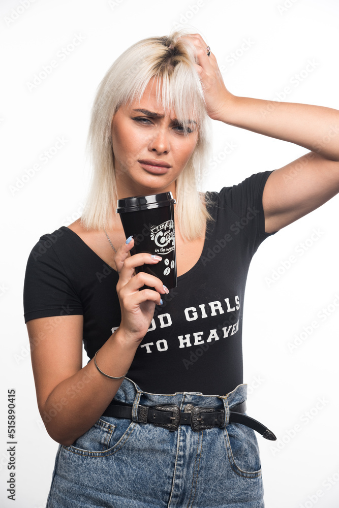Young woman holding cup of coffee on white background with serious expression