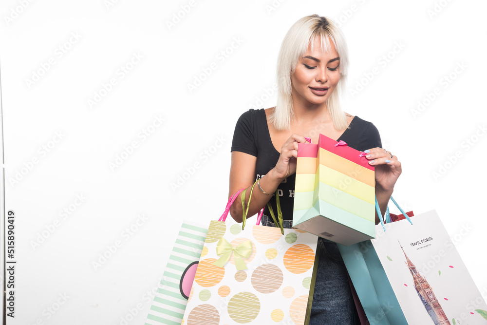 Young woman holding and looking at shopping bags on white background Young woman holding and looking at shopping bags on white background