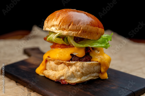 beef burger with melted dripping cheese on black wooden board