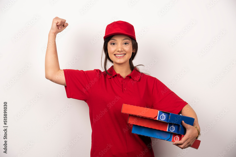 Happy female pizza delivery worker standing in white background with three cardboards of pizza Happy female pizza delivery worker standing in white background with three cardboards of pizza