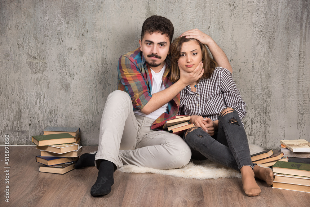 Obraz premium Photo of young couple sitting on the floor with books