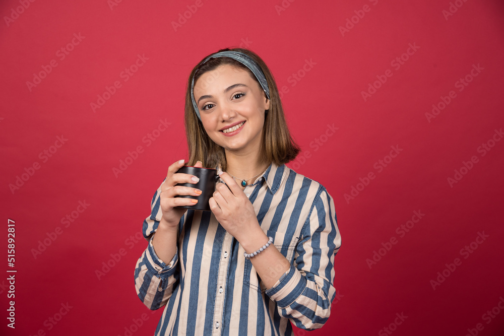 Cheerful woman holding cup of coffee and posing to camera Cheerful woman holding cup of coffee and posing to camera