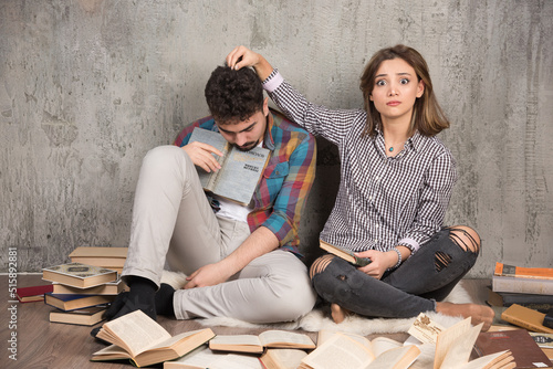 Image of pretty couple sitting on the floor with a lot of books