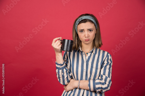 Young woman holding cup of coffee with sad expression