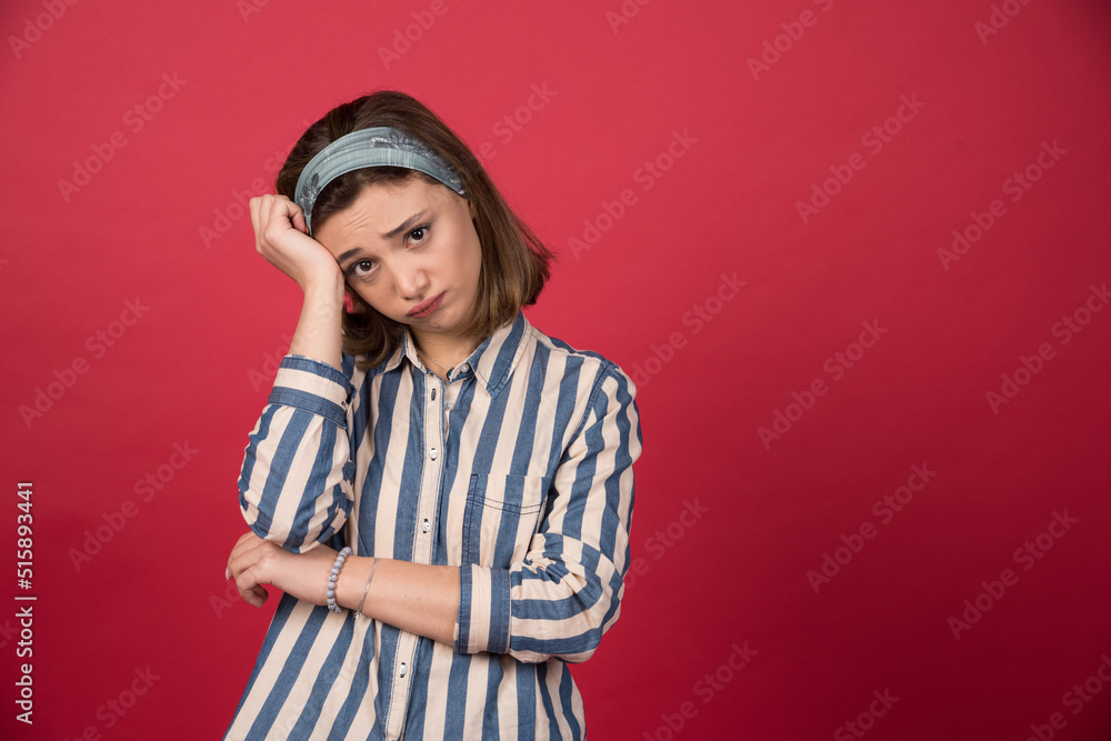Beautiful girl with dejected look standing on red background Beautiful girl with dejected look standing on red background