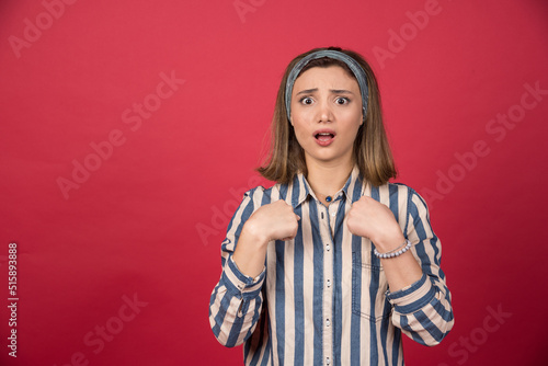 Female teenager in striped shirt pointing at herself