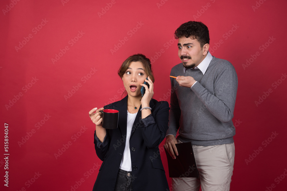 A young woman talking on smartphone near angry boyfriend A young woman talking on smartphone near angry boyfriend