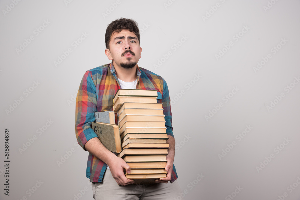 Exhausted student trying to hold bunch of heavy books Exhausted student trying to hold bunch of heavy books
