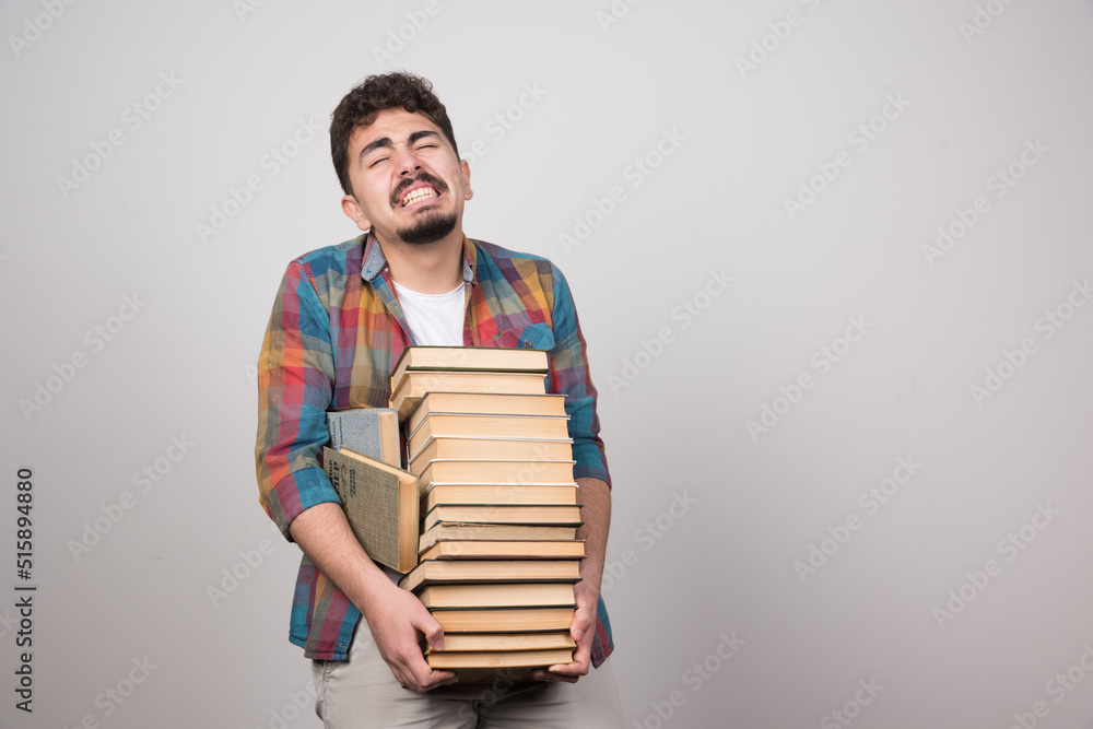 Exhausted student trying to hold bunch of heavy books Exhausted student trying to hold bunch of heavy books