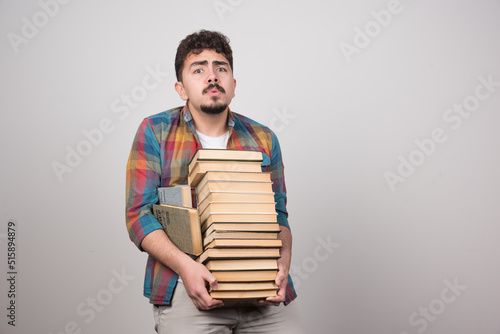 Exhausted student trying to hold bunch of heavy books