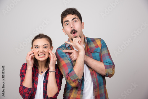 Young happy couple standing and posing on a gray wall