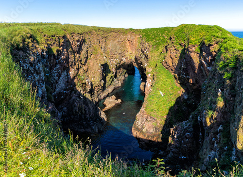landscape view of the Bullers of Buchan Sea Cave and sinkhole with many birds nesting on the cliffsides