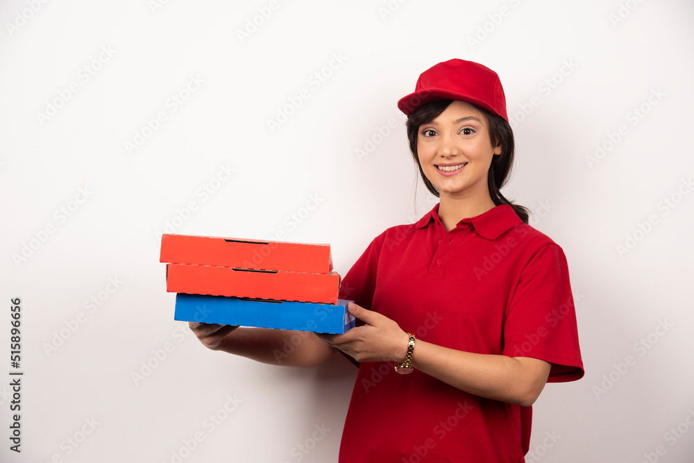 Happy female pizza delivery worker holding three cardboards of pizza Happy female pizza delivery worker holding three cardboards of pizza