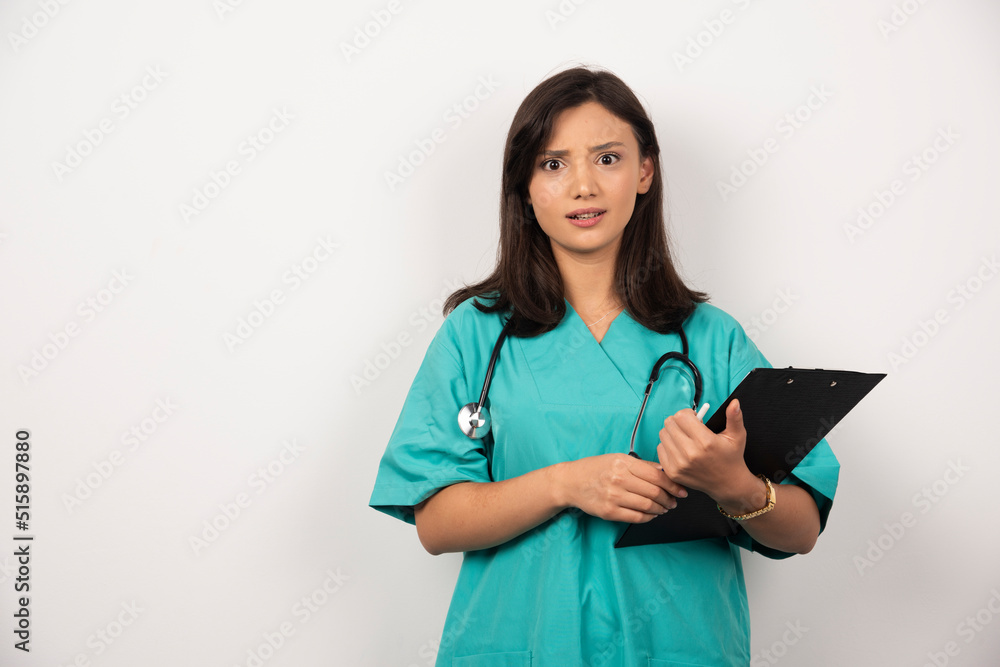 Doctor with stethoscope and clipboard looks surprised on white background Doctor with stethoscope and clipboard looks surprised on white background