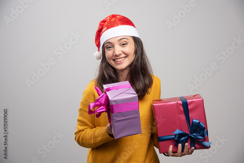 Young woman in Santa hat holding gift boxes