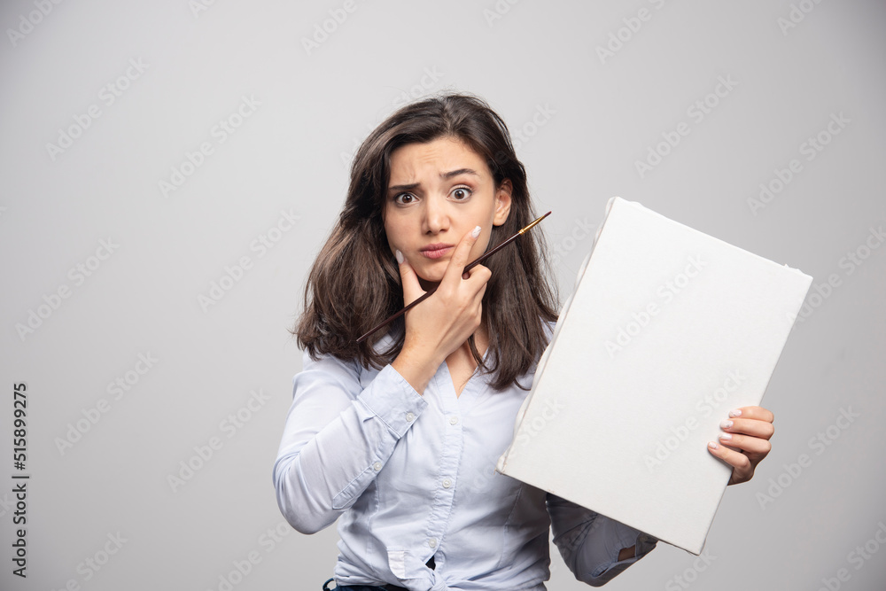 Young girl holding empty canvas and thinking about something Young girl holding empty canvas and thinking about something