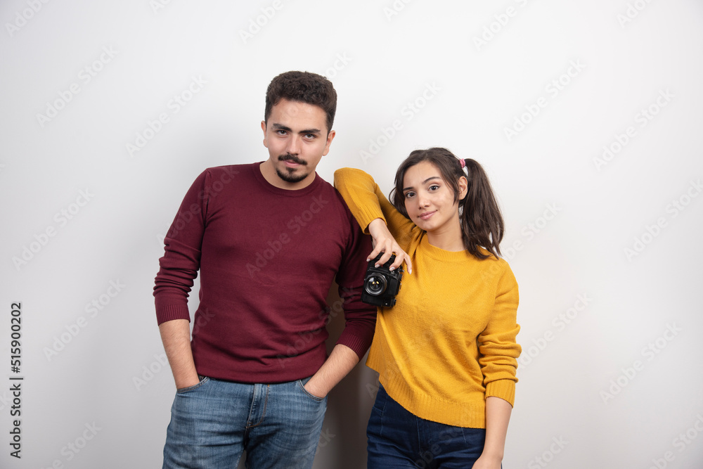 Cute couple posing with camera over a white wall Cute couple posing with camera over a white wall