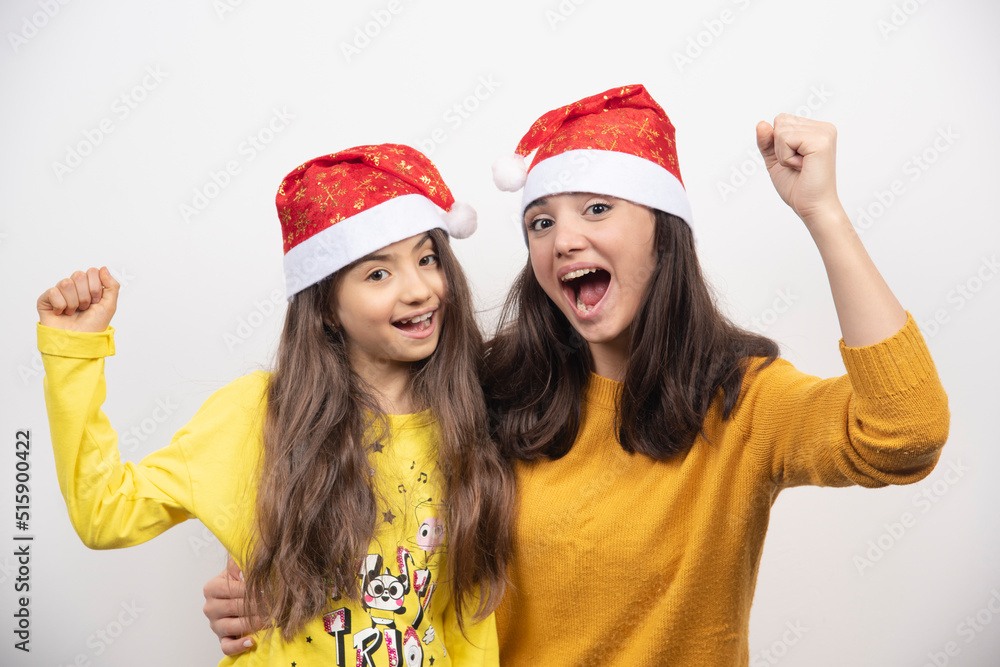 Woman hugging young girl with Santa Claus red hat Woman hugging young girl with Santa Claus red hat