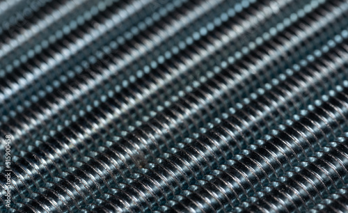 The threaded bolts are stacked side by side to create an abstract structure. Enlarged metal threaded rods. Abstract metal background.