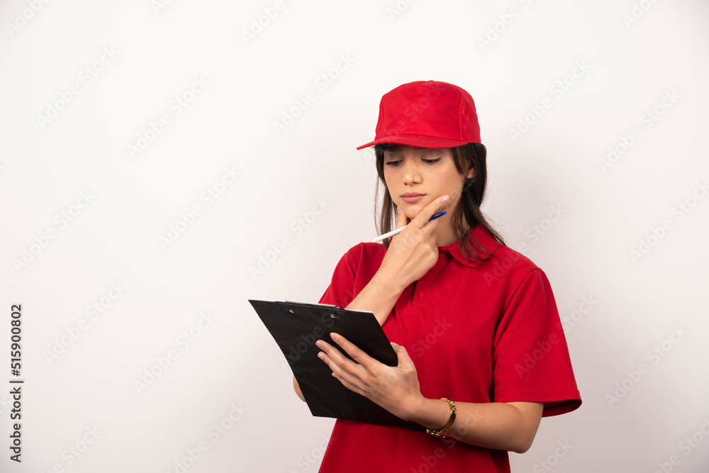 Young delivery woman in red uniform with clipboard on white background Young delivery woman in red uniform with clipboard on white background