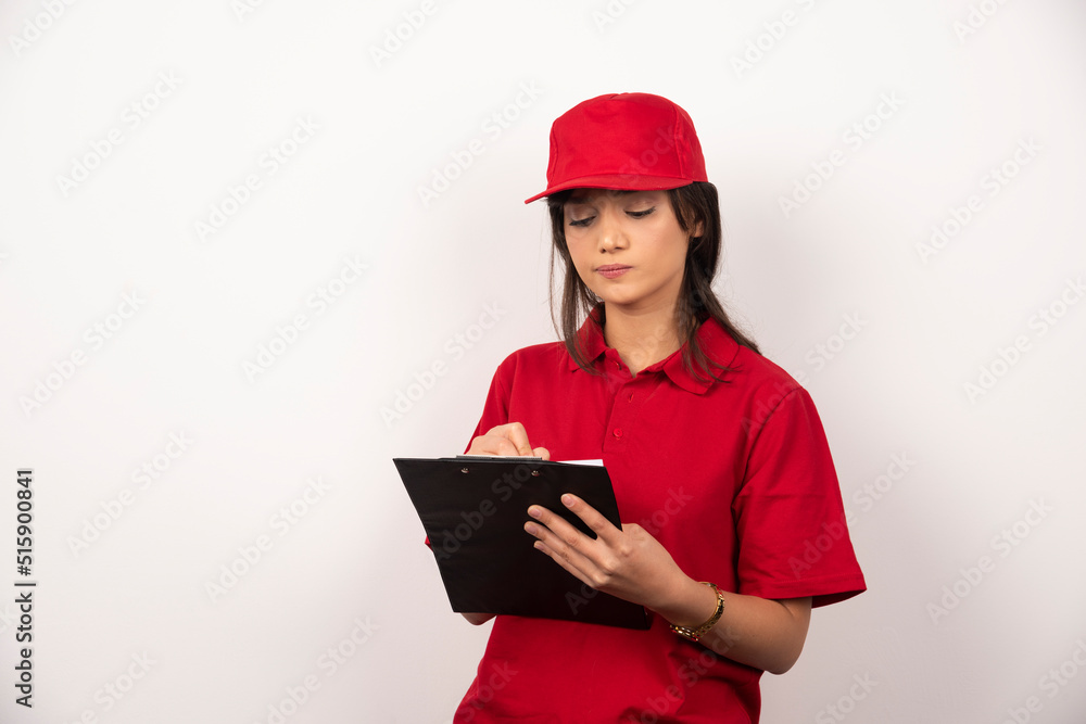 Young worker with red uniform and clipboard on white background Young worker with red uniform and clipboard on white background