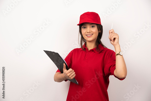 Young delivery woman in red uniform with clipboard on white background