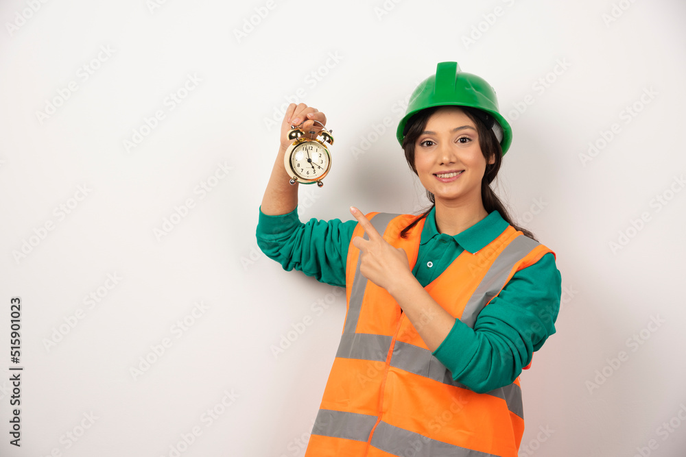 Female employee pointing at clock on white background Female employee pointing at clock on white background